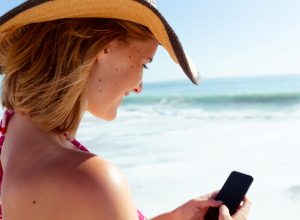 lieux pour devenir libertin avec une belle femme sous le soleil coiffé d'un chapeau de paille et sur son tel